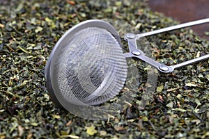 Green tea with herbs in sieve on a wooden board