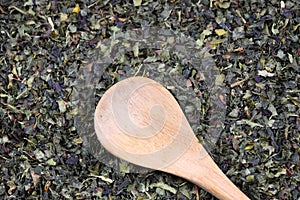 Green tea with herbs in wooden spoons on a wooden board