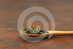 Green tea with herbs in wooden spoons on a wooden board