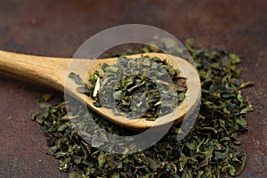 Green tea with herbs in wooden spoons on a wooden board