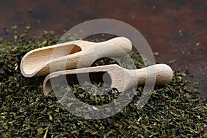 Green tea with herbs in wooden spoons on a wooden board