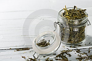 Green tea leaves sencha in jar on wooden background