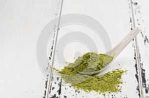 Green tea match powder in a white ceramic spoon on white