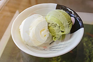 Green tea matcha ice cream scoop in white bowl from top-view isolated on white background. Pistachio, coconut, milk ice cream on c