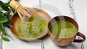 Green tea matcha powder in a wooden bowl with a whisk and wooden spoon