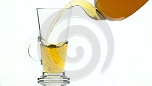 Green tea pouring into glass cup from teapot on white background