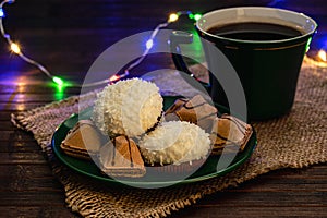 Green tea set. Coconut souffle cakes and crispy biscuits on a saucer with a cup of coffee or tea. Photo in a dark key, subdued
