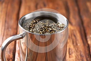 Green tea in a stainless steel mug on an old wooden table