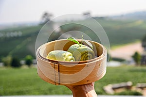 Green tea steamed bun on wooden basket in tea plantation