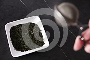 green tea and tea strainer on background