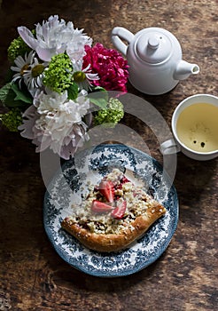 Green tea, strawberry crumb foccacia and a bouquet of summer flowers on a wooden background, top view