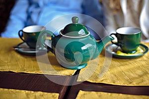 Green teapot and two cups of tea