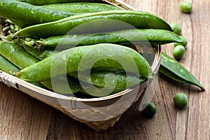 Green, tender, fresh and raw peas. Close-up and top view. Rustic appearance. Rustic appearance. Wooden background