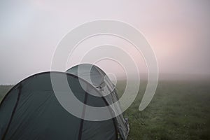 green tent on background of mountain plateaus in mist of clouds