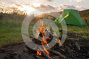 Green tent and campfire at sunset