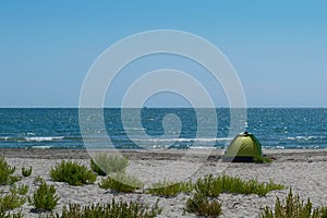 Green tent installed on remote wild beach. Enjoy a vacation on the sea side while maintaining social distance