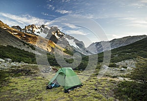 Green tent in mountains at sunrise