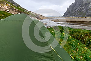 Green tent standing at Bunes Beach on Lofoten Islands in Norway