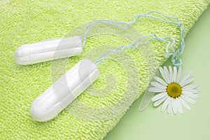 Green terry bath towel, chamomile flower and menstrual woman tampons for blood period hygiene. Woman critical days, gynecological