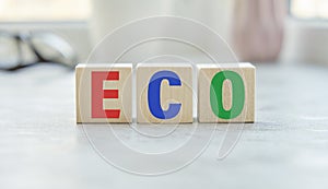 Green text ECO is written on vertical wooden cubes on table with many wooden blocks