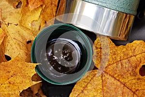 Green thermos stailess steel cup in autumn leaves photo