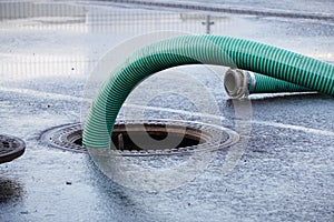The green thick hose from a sewer pit, pumping sewage or sewage from collector in city. water drainage. Sewer manhole