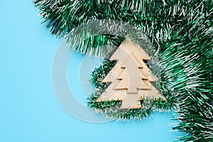 Green tinsel and Christmas tree toy on light blue background, flat lay. Space for text