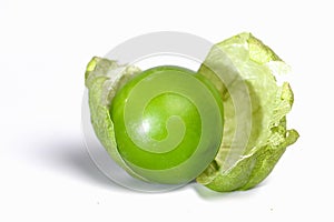 Green tomatillo on white table covered with the peel