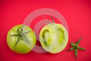 Green tomatoes on red backgeround photo