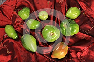 Green tomatoes ripen on a red fabric. group of green tomatoes on top of a fabric