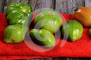Green tomatoes ripen on a red fabric. group of green tomatoes on top of a fabric