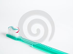 The green toothbrush with a red blue and white striped toothpaste