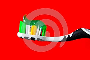 Green toothpaste beautifully lies on a toothbrush on a red background