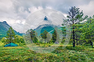 Green tourist tent near on the meadow Innerdalsvatna lake. Foggy morning scene in Norway, Europe. Beauty of nature concept