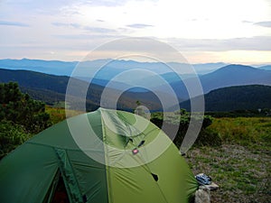 Green tourist tent in ukrainian mountains with a view to forested hills