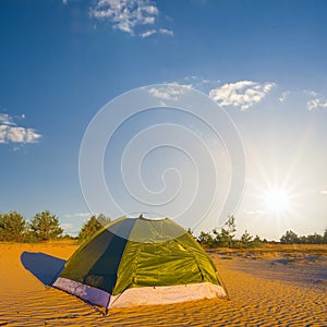 green touristic tent stay among sandy desert at the sunset