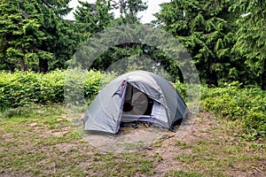 Green touristic tent in turist camp, in a forest among bushes and trees. Nature background