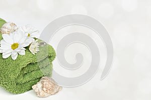 Green towel, shells and flowers on white background