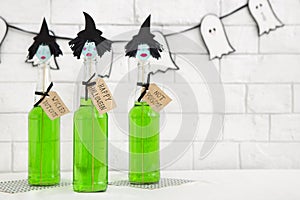 Green toxic cocktails with witches heads over white bricks wall photo