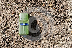 Green toy car with blue lamp on the roof on the ground background. The view from the top. Copy space. Soft selective focus