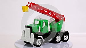Green toy crane truck scale model car rotating on white background.