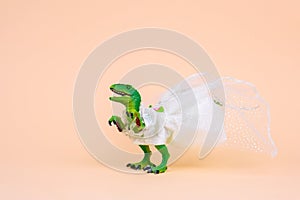 green toy dinosaur wearing white wedding dress on a pastel background. Humour wedding card