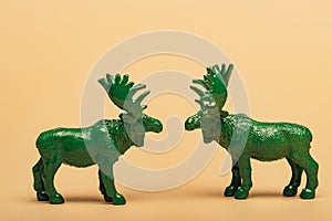 Green toy mooses on yellow background photo