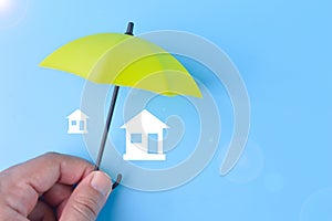 Green toy umbrella and house symbols. Insurance coverage concept