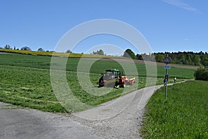 A green tractor equipped with a grass-cutting mechanism was photographed.