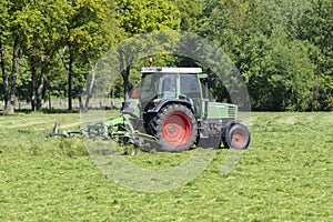 Green tractor mowing tall green grass