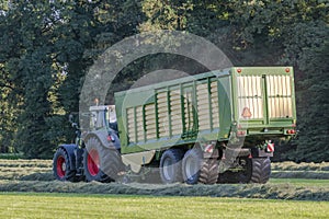 Green tractor picking up cut grass