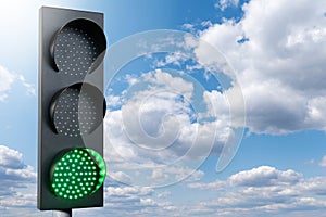 Green traffic light on a background of blue sky. Symbol of sustainable energy and development