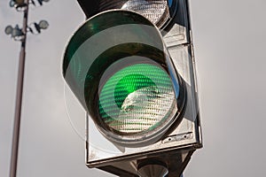 Green traffic light on gray sky background