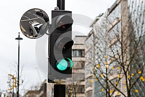 Green Traffic Light Signal and Traffic Convex Mirror with the Reflection of the vehicle, London, England, UK